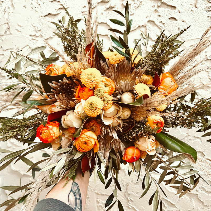Rustic bronze and orange fall wedding bridal bouquet featuring ranunculus and mums.
