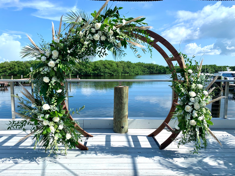 All white beach boho round wedding arch flowers with roses, eucalyptus, and pampas grass.