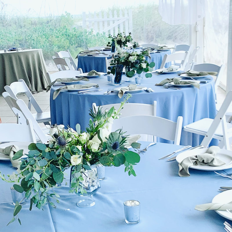 Blue theme wedding. Asymmetric floral design heavy on mixed eucalyptus, blue thistle and white garden blooms. In silver compote vases.