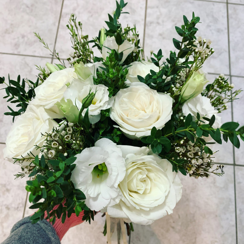 All white classic garden bridal bouquet of roses, lisianthus, and lush mixed greenery.