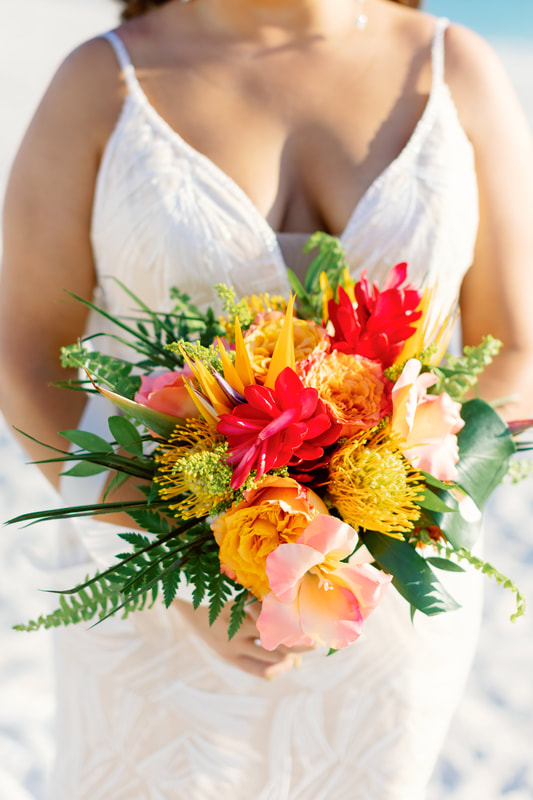 Bright tropical bridal bouquet perfect for a beach wedding. Ginger, proteas., roses, birds of paradise, and tropical greenery.