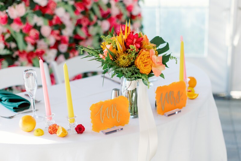 Tropical wedding at Sirata Beach Resort in St Pete, FLorida. Bridal sweetheart table with brides bouquets, colorful taper candles, and flower wall.