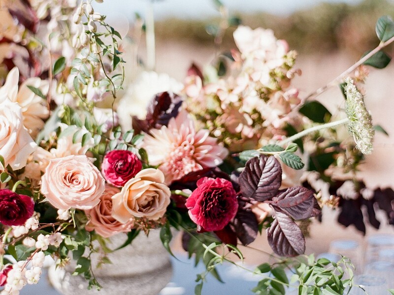 Rustic fall romantic centerpiece in burgundy, peach, blush, and toffee colors using roses and ranunculus.