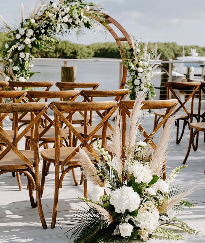 All white beach boho round wedding arch flowers and back of aisle decor with roses, eucalyptus, and pampas grass.