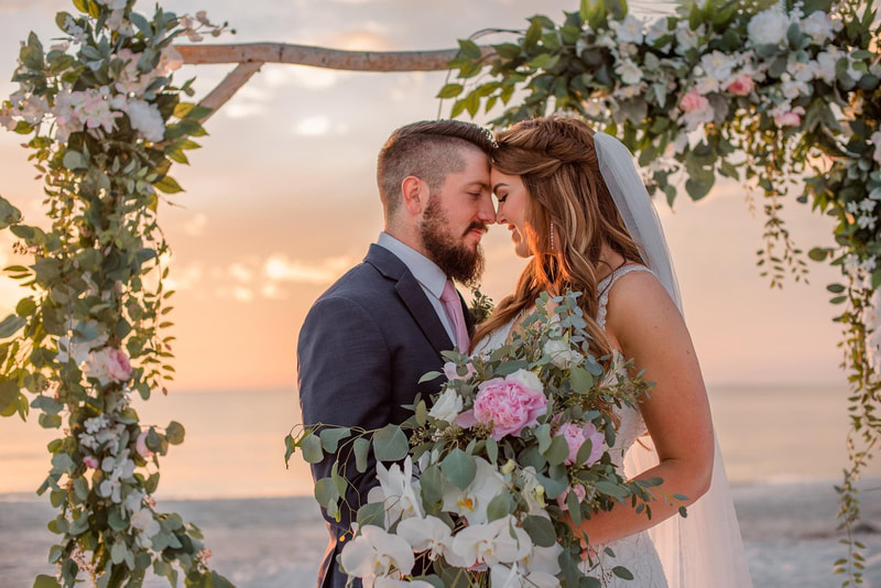 Garden wedding at the beach. Birch wedding arch covered in wispy foliage and pink and white garden flowers. Lush cascading bridal bouquet to match.