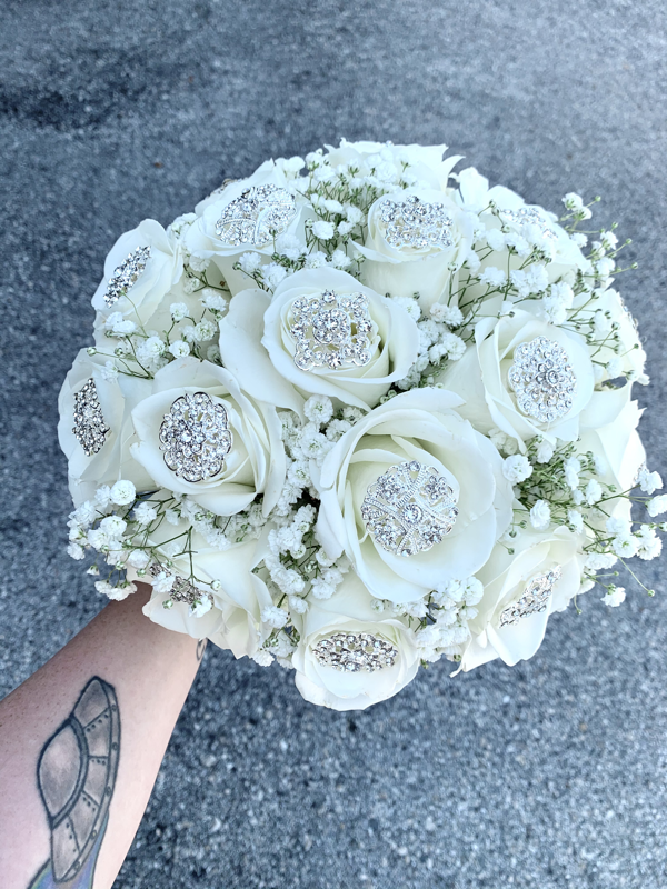 White rose and baby’s breath bridal bouquet covered in rhinestone broaches.